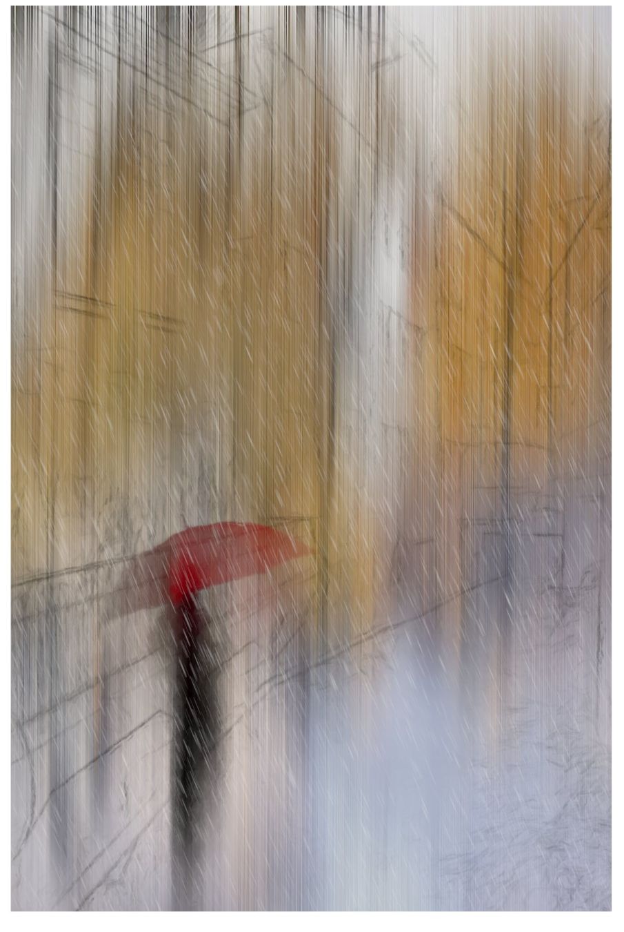 In der Stadt. Es ist Herbst. Eine Frau mit einem roten Regenschirm steht am Straßenrand.